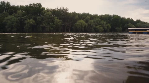 Sunset reflecting off lapping lake or river water. Shooting from water surface Stock Footage 133081387