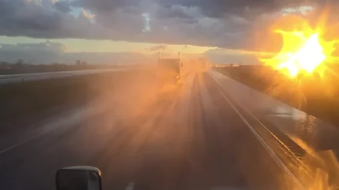 Sunset reflecting off a wet highway through a windshield Stock Footage 281764207