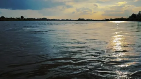 Sunset reflecting on wide river surface under dramatic clouds. 4k video 60 fps Stock Footage 340441551