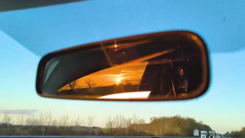 Sunset reflection in car rearview mirror while driving on highway Stock Footage 340533330