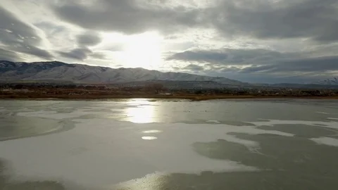 Sunset Reflection Off Frozen Lake with Mountains Vídeos de archivo 70866745