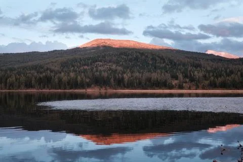 Sunset reflection of a mountain peak on the calm surface of Yazevoe lake in.. 写真素材