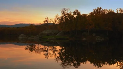 Sunset Reflection Over a Tranquil Lake with Autumn Trees and Mountains Stock Footage 293916174