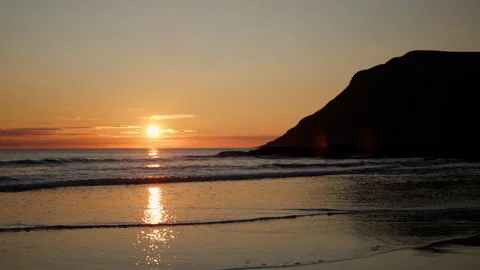 Sunset Reflection on Quiet Nordic Beach with Dark Headland Silhouette Stock Footage 340574605