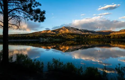 Sunset reflection of red rock cliff in calm lake. Stock Photos