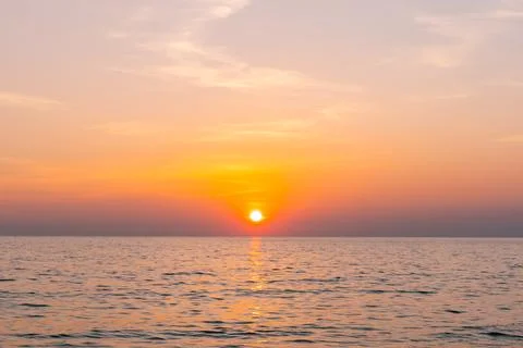 Sunset reflection sea. beautiful sunset behind the clouds and blue sky abov.. 스톡 사진