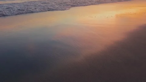 Sunset Reflection in Wet Sand with Calm Wave coming ashore in Slow Motion Vidéo 333110990