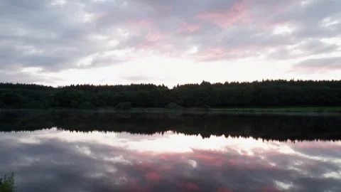 Sunset reflections over calm lake in forested area Stock Footage 310241056