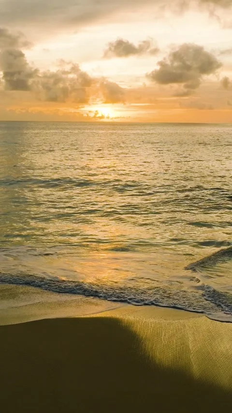 Sunset reflections on a serene ocean shore with gentle waves. Seychelles, Mahe. Stock Footage 303472230