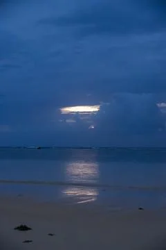 Sunset reflections on tranquil waters under a moody sky Stock Photos