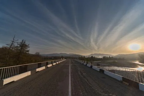 Sunset on the river. the clear blue sky. road leading to the mountains. Stock Photos