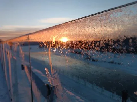 Sunset on the river, the sun is reflected in the glass railing Stock Photos