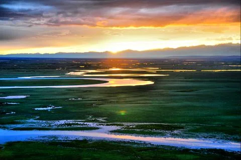 Sunset River Wetland Landscape with Dramatic Sky and Mountains Stock Photos