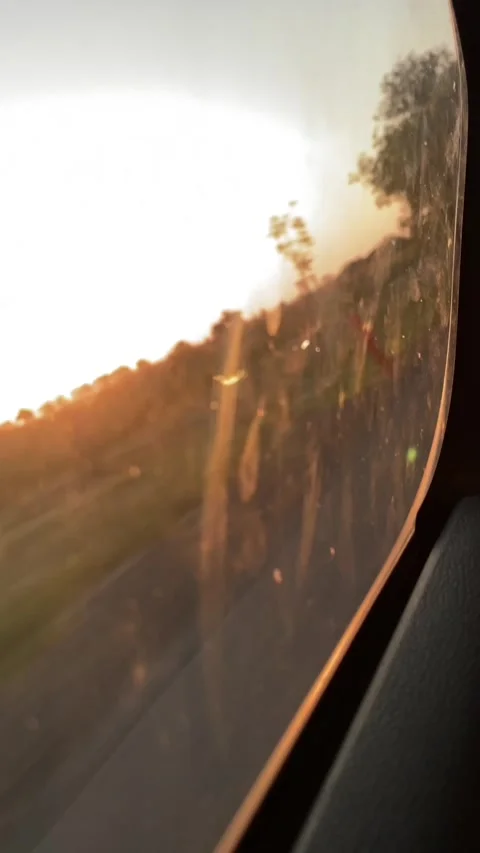 Sunset roadside view through curved vehicle window with warm sunflare and blur Stock Footage 341662850