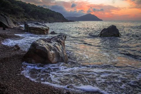 Sunset of rocks beach  with orange clouds in sky Stock Photos
