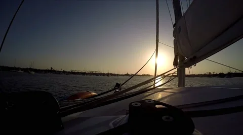 Sunset on sailing catamaran motoring into harbor with sun in the ropes. Video stock 67579862