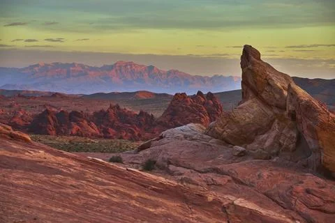 Sunset Sandstone Formations and Distant Mountains in Vibrant Desert Landscape Foto stock