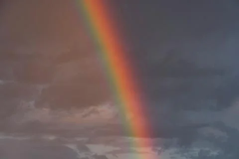 Sunset scene with a rainbow, emanating from bottom edge Warm pink and orange  Stock Photos