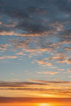 Sunset scene with scattered clouds, orange, yellow, and blue hues, horizon .. Stock Photos