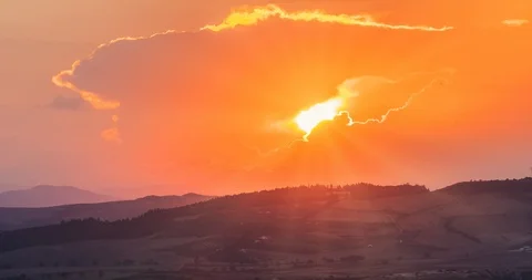 Sunset scene with sun fall behind the clouds and mountains in background Stock Footage 99513791