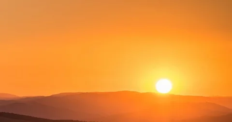 Sunset scene with sun fall behind the clouds and mountains in background Stock Footage 100385239