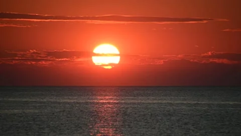 Sunset at sea, big red disk of sun move behind the clouds Stock-Footage 160116453