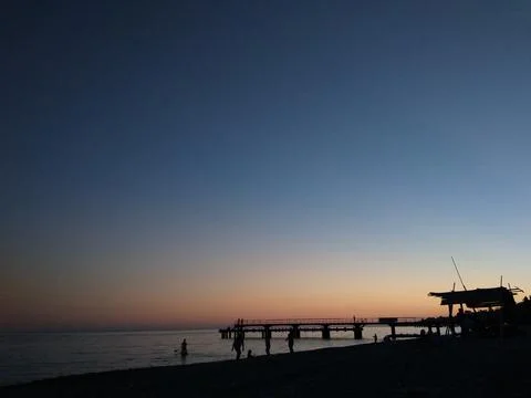 Sunset on the sea. Blue-orange. People and pier, contrasts. Stock Photos