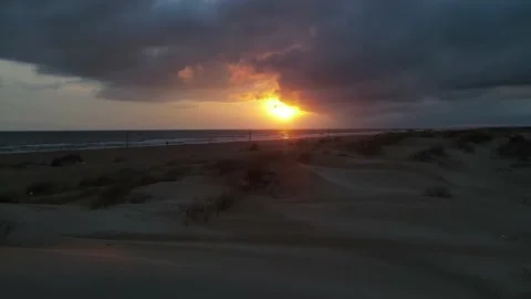 Sunset on the sea, the camera rises from behind a hill with sand, desert Stock Footage 220624052