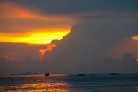 Sunset on sea cloud and ray colorful sky fishing boat and on island 库存照片