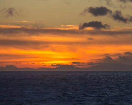 Sunset at sea with mountains in the background Stock Photos