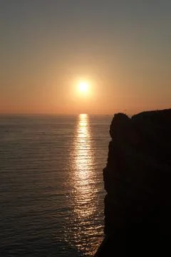 Sunset by the sea with northern gannets on a cliff and in the air Stock Photos