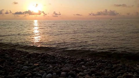 Sunset on the sea from a pebble shore in backlight with yellow and gold sky Stock Footage 128504493
