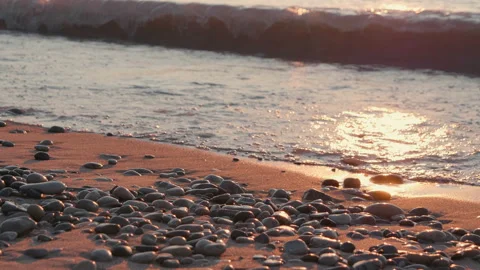 Sunset at sea, sandy beach with pebbles, sun reflection in water, waves Stock Footage 111634767