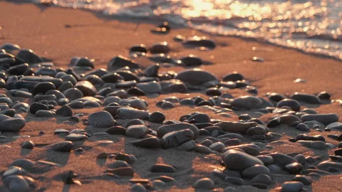 Sunset at sea, sandy beach with pebbles, sun reflection in water, waves Видео 111639790