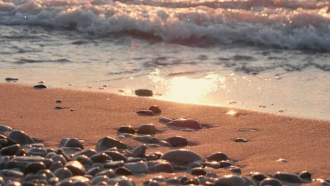 Sunset at sea, sandy beach with pebbles, sun reflection in water, waves Stock Footage 111642186