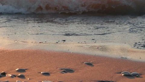 Sunset at sea, sandy beach with pebbles, sun reflection in water, waves 库存影片 111643650