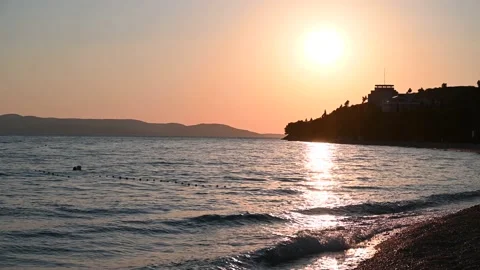 Sunset at the sea. The setting sun with silhouette of mountains. Sea waves. Stock Footage 155131200