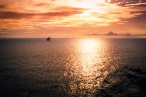 Sunset at the sea with a ship in distant plane Stock Photos