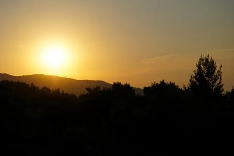 Sunset at the sea. Sun falling down behind mountain Stock Photos