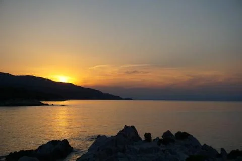 Sunset at the sea. Sun falling down behind mountain Foto stock