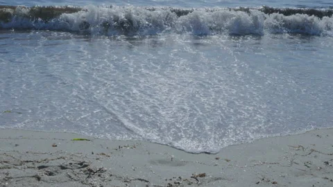 Sunset sea waves crashing on a sandy beach with the sun in the background Vídeo Stock 139037951