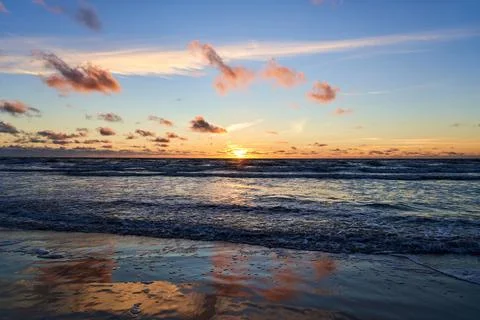 Sunset on the seashore. Strong sea waves beautifully wash the shore against.. Stock Photos