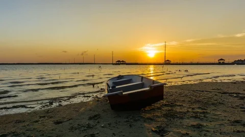 Sunset at the seaside with red boat as the foreground Stock Footage 76673273