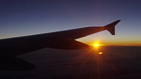 Sunset seen under the wing of an airplane just as the sun sets Stock Footage 268422715