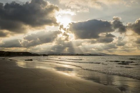 Sunset at a Serene Beach with Dramatic Clouds and Reflections Stock Photos