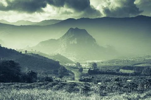 Sunset is shading to mountain behind cloudy sky Stock Photos