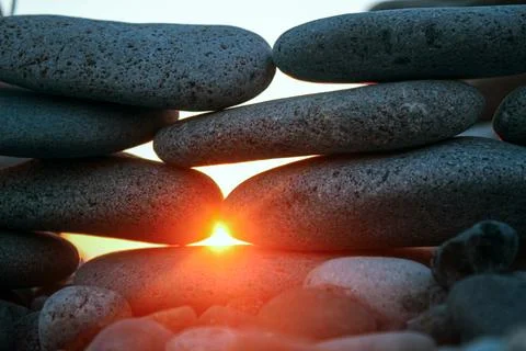 Sunset shining between stones on the seaside coast Stock Photos