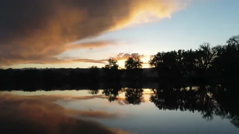 Sunset shown in lake - Drone camera moves forward, down, and backward Stock Footage 137863292