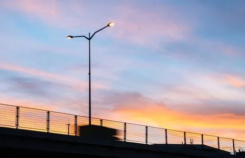 Sunset silhouette of an elevated bridge with illuminated streetlights. Stock Photos