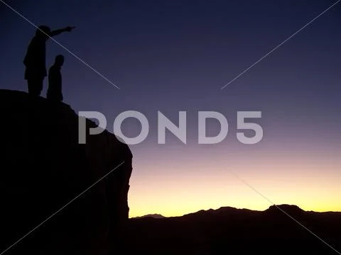Sunset Silhouette - Men standing on big rock in Joshua Tree National Park Stock Photos